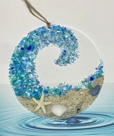 a glass ornament with blue and white beads on the bottom is in water