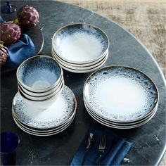 a table topped with plates and silverware on top of a black marble countertop