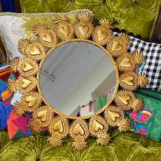 a mirror sitting on top of a green couch next to pillows and other decorative items