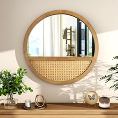 a round mirror sitting on top of a wooden table next to a potted plant