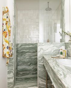 a bathroom with marble counter tops and white tiles on the walls, along with a shower