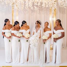 a group of women standing next to each other in front of a white wall with flowers