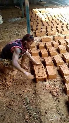 a man laying on the ground in front of blocks of wood with bricks stacked up behind him