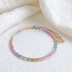 Our Shimmer Rainbow bracelet is made to catch the light when you move with rainbow coloured glass beads and silver sliding clasp to adjust length.  The silk cord is a pale pink colour and the beads are high quality glass beads in pink, peach, yellow, green, pale blue and lilac. Fits an average wrist size of up to 7 inches and tightens to 6.25in. Extends to maximum of 8.5in to fit over the widest part of the hand. If you have a small wrist and hands and would like a smaller bracelet size please contact me. Displayed in one of our pretty gift boxes, so fantastic as a present for a friend or to yourself! Check out the matching necklace https://www.etsy.com/uk/listing/1279385760/beaded-shimmer-rainbow-necklace-dainty Shipping Uk: 2-3 days - Royal Mail 48hr tracked International standard delive Lilac Fits, Sead Bead Necklace, Valentine Gifts For Boys, Diy Jewelry Set, Braided Bracelet Diy, Silk Bracelet, Valentine Gifts For Girlfriend, Beading Jewelery, Double Wrap Bracelet