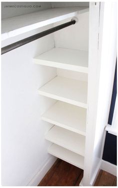 an empty closet with white shelves and wood flooring