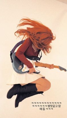 a woman with long red hair is holding a guitar and posing for the camera while flying through the air