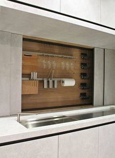 a kitchen counter with wine glasses and utensils in the cabinet space above it