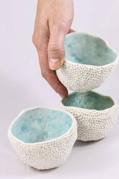 a person is holding two bowls with their fingers on them and they are sitting next to each other