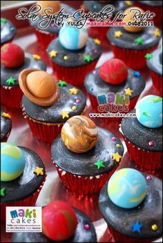 cupcakes decorated with space themed icing and stars on top are sitting in a tray