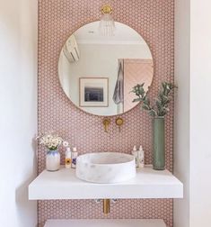 a white sink sitting under a round mirror in a bathroom next to a wall mounted faucet