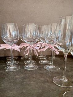 several wine glasses with pink bows are lined up