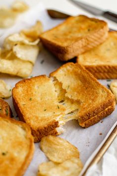 toasted pieces of bread with cheese and herbs on them next to utensils