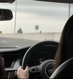 a woman driving down the road in her car with another person behind her looking out the window