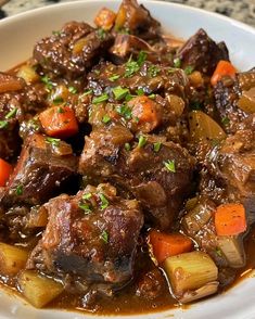 a white bowl filled with stew and carrots