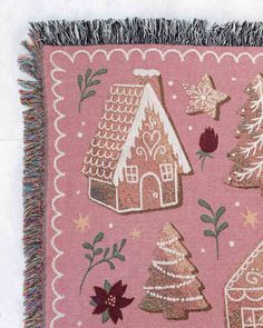 a pink blanket with gingerbread houses and poinsettis on it, fringe trimming around the edges