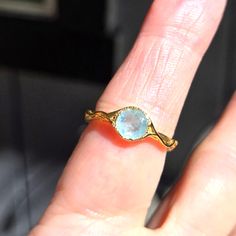 a woman's hand with a ring on it that has a blue stone in the middle