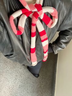 a person in a black leather jacket is holding a red and white striped candy cane