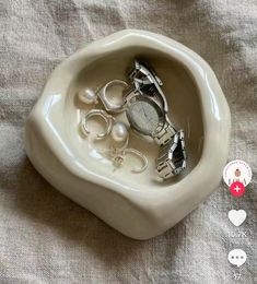 a ceramic heart shaped bowl with two watches in it and hearts attached to the handles