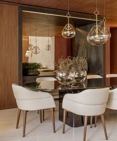 a dining room table with white chairs and chandelier hanging from it's ceiling