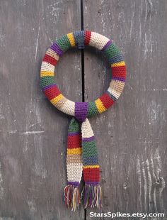 a multicolored knitted scarf hanging on a wooden door