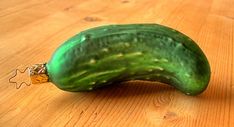 a green cucumber sitting on top of a wooden table next to a piece of puzzle