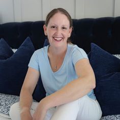 a woman sitting on top of a bed smiling at the camera with her legs crossed