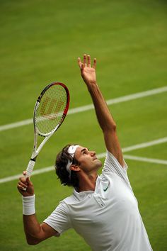 a man holding a tennis racquet on top of a tennis court with his hands in the air