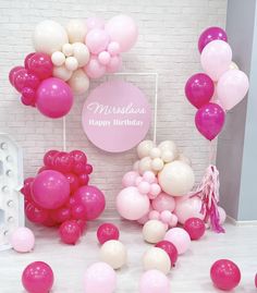 pink and white balloons are on display in front of a brick wall