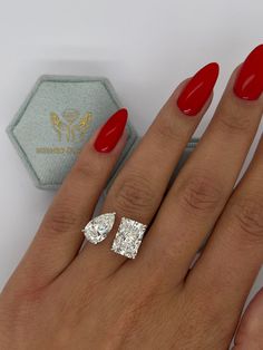 a woman's hand with red nail polish and two engagement rings on her fingers