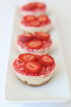 strawberry cheesecakes are lined up on a white plate