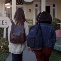 two women walking down a sidewalk carrying backpacks on their backs, with the words antiques in front of them