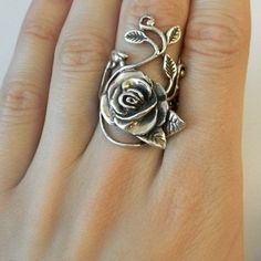 a woman's hand with a silver rose ring on top of her finger,