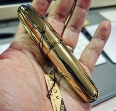 a person holding a gold pen in their left hand with a price tag on it