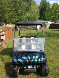 a blue and black golf cart parked in the grass