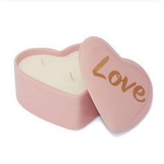 a pink heart shaped candle with the word love on it