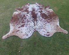 a brown and white cowhide rug on grass