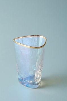 a clear glass with gold rim sitting on top of a white countertop next to a blue wall