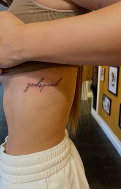 a woman with a small tattoo on her stomach that reads, godfad in cursive writing