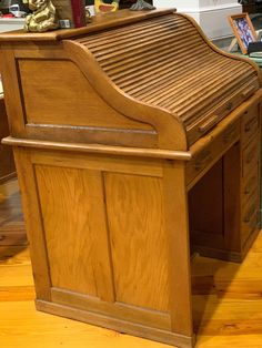 a wooden desk sitting on top of a hard wood floor next to a shelf filled with books