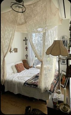 a white bed sitting under a window next to a lamp on top of a wooden floor