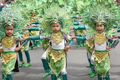 children in green and gold costumes are marching down the street with their hands on their hipss