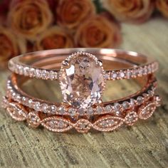 two rose gold wedding rings set with an oval cut diamond surrounded by smaller pink and white diamonds