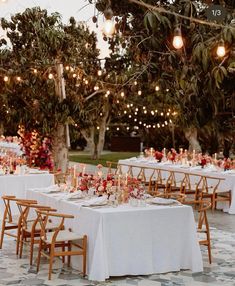 an outdoor dining area with white tablecloths and wooden chairs, lit by string lights