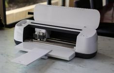 a white and black machine sitting on top of a table next to a printer screen