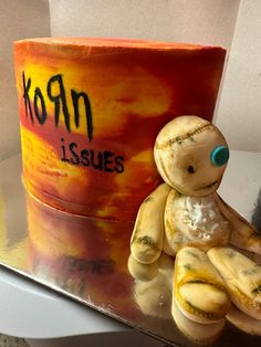 a cake shaped like a teddy bear sitting in front of a cup with the word korn issues written on it