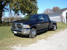 a black ram truck parked in front of a house on the side of a road