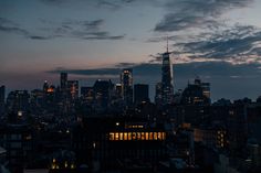 the city skyline is lit up at night, with skyscrapers in the foreground