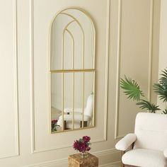 a living room with a chair, mirror and potted plant