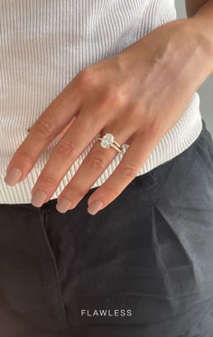 a woman's hand with a ring on her left wrist and black pants underneath