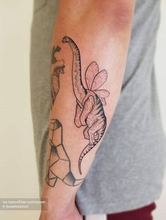 a man's arm with a dinosaur tattoo on it and a flower in the middle